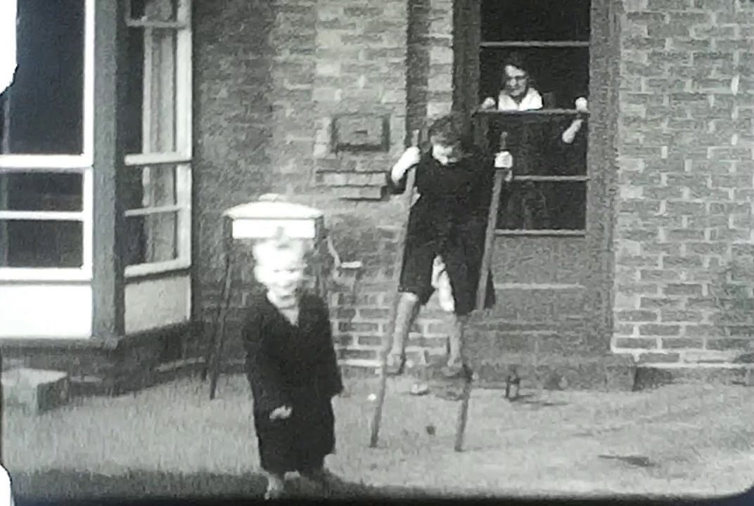 A still image from a film showing a family practicing on Stilts on Boxing Day 1954.