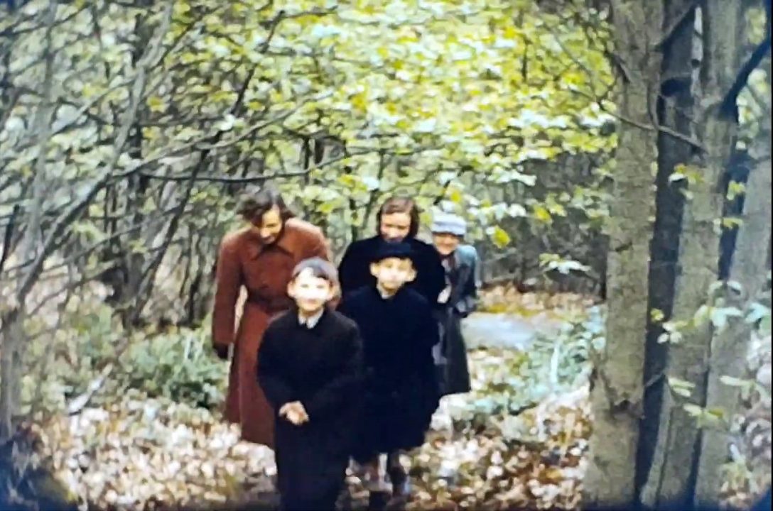 A still image from a vintage home movie made in 1958 showing a family taking a walk in the countryside.