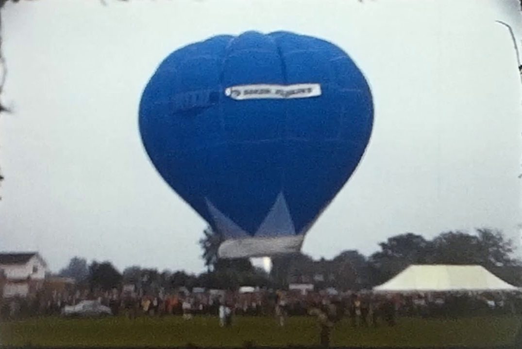 A still image from a vintage home movie showing a hot air balloon being launched