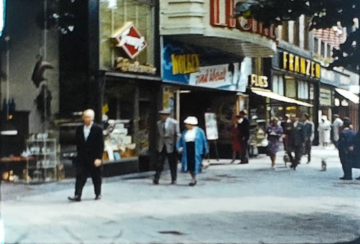 A still image showing a row of shops from a vintage home movie taken in Germany and Holland in 1961