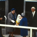 A still image from a standard 8 vintage home movie which shows an opening ceremony somewhere.