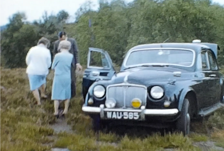 A still image from an 8mm film featuring a livestock farm and a holiday near a large weir