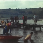 A still image from a vintage home movie which shows speed boats racing on a lake or waterway
