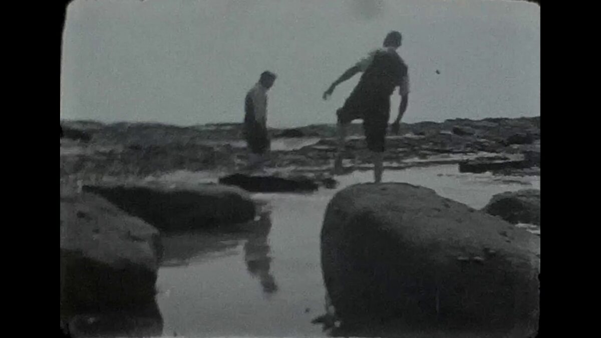 A Still image from a black & white film by a rocky seafront