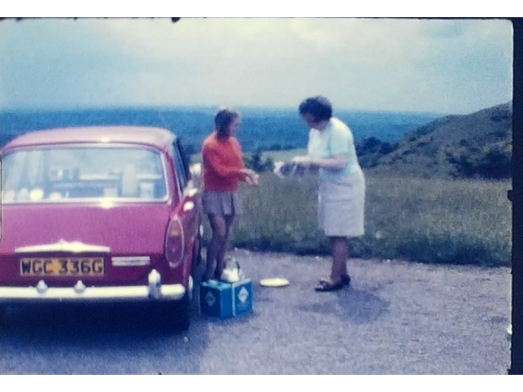 A photo of a woman and her daughter standing by a 1968 Morris car