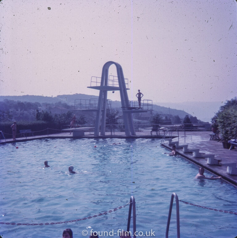 A diver on a diving board above a swimming pool