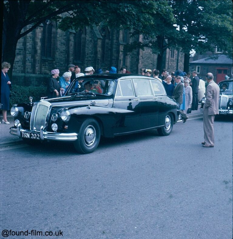 A group of people surrounding a car at a wedding