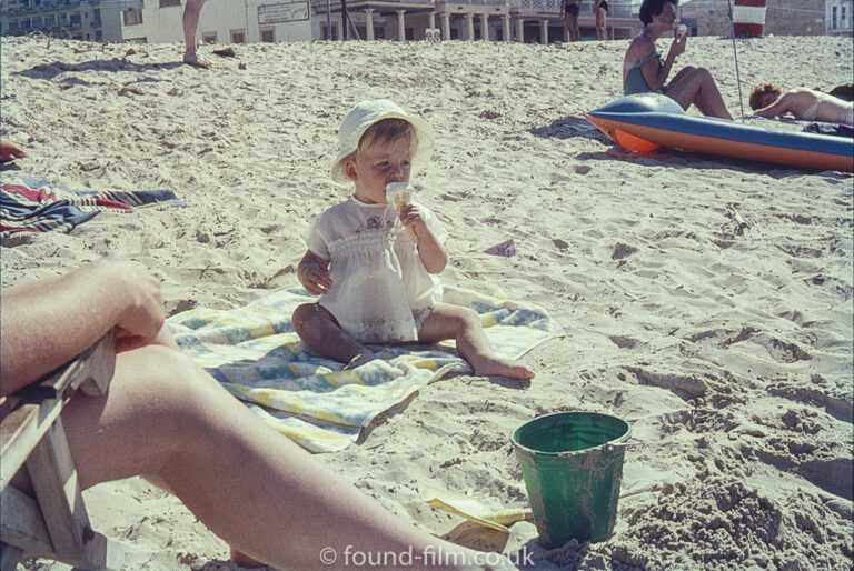 Baby on a beach eating an ice-cream