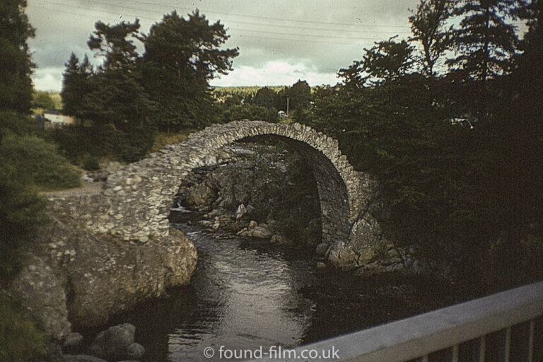 Arched stone footbridge over a stream.