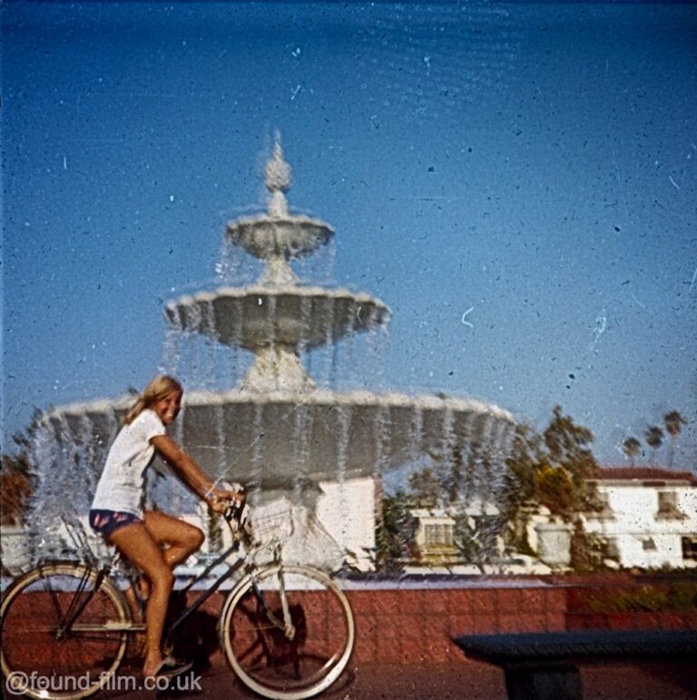 A girl on a bike in front of a fountain