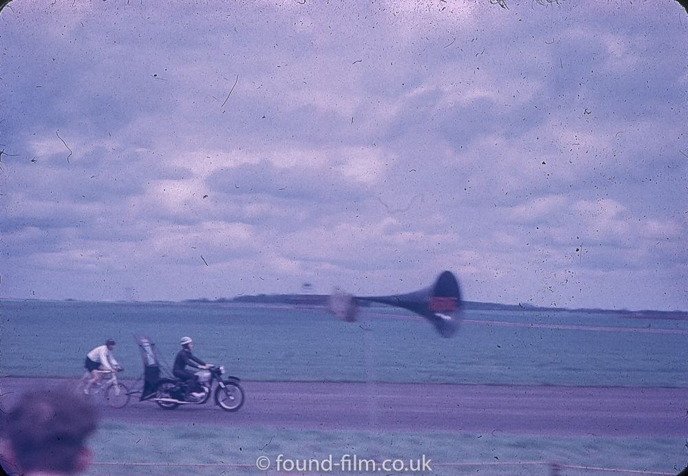 A cyclist at a 1950s motor racing event