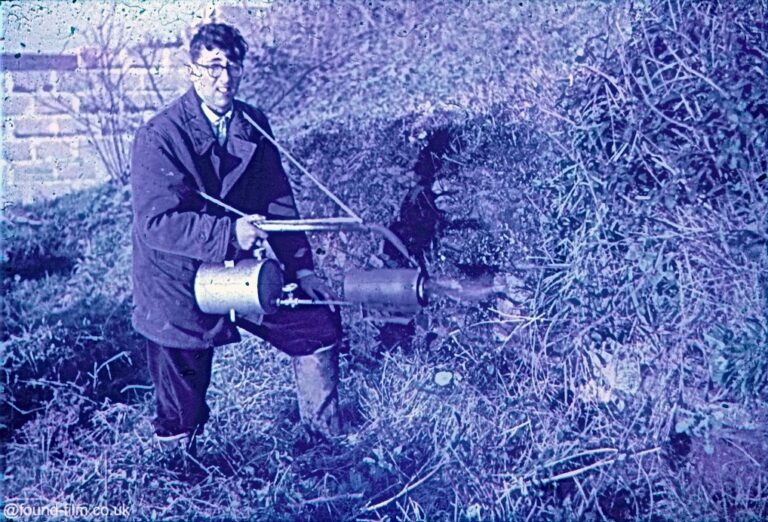 A gardener with a flame thrower clearing plants