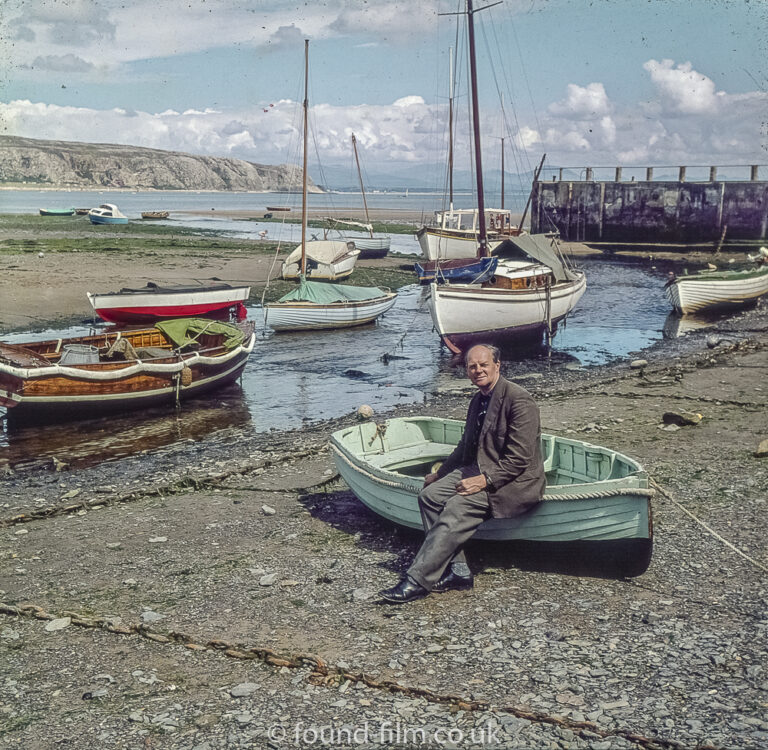 A Man sitting on a green boat by the sea