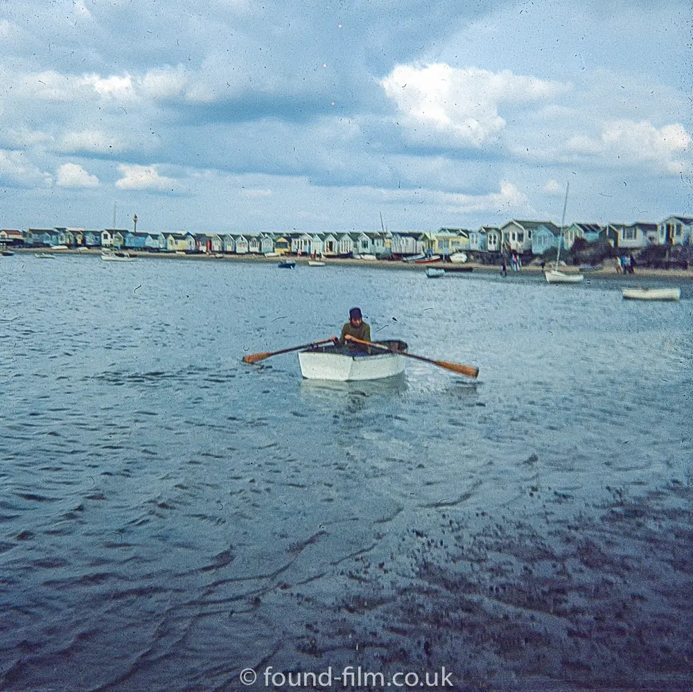 A man rowing a dingy close to the beach