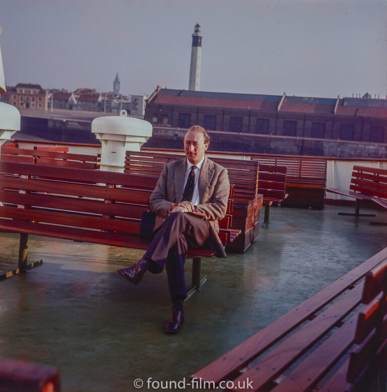 A man seated on a boat in the late 1950s