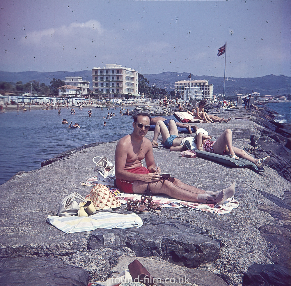 Man sunbathing and writing on Rocks early 1960s