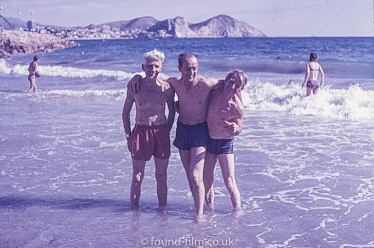 Three men standing in the sea on a beach