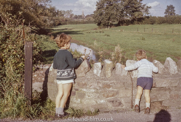 Two children looking over a stone bridge