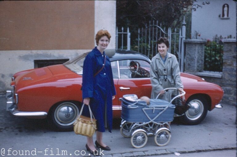 Two women and a baby by a red sports car, 1958