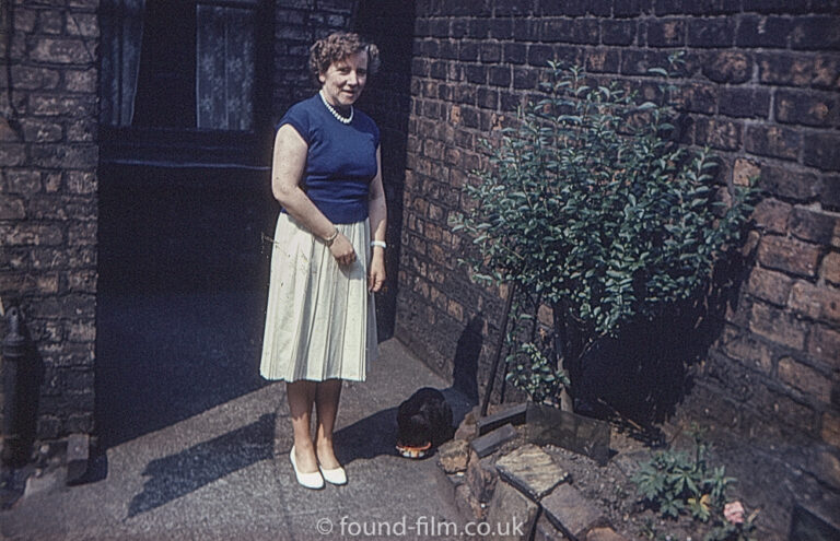 Woman with a dog standing next to a brick wall