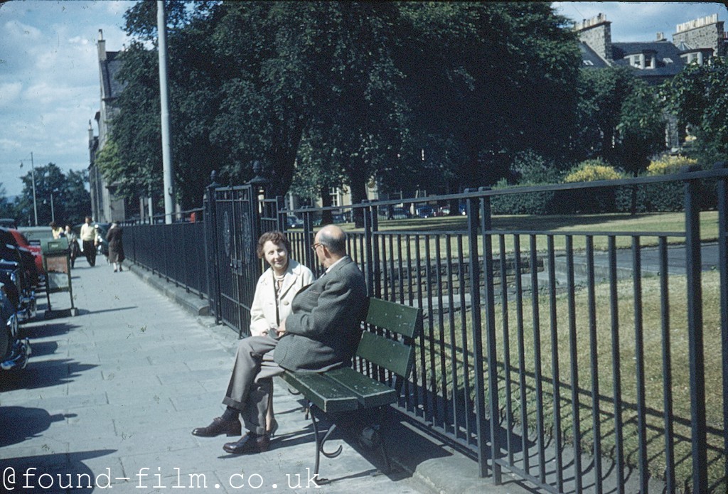 Couple sitting on a bench by a park - c1962