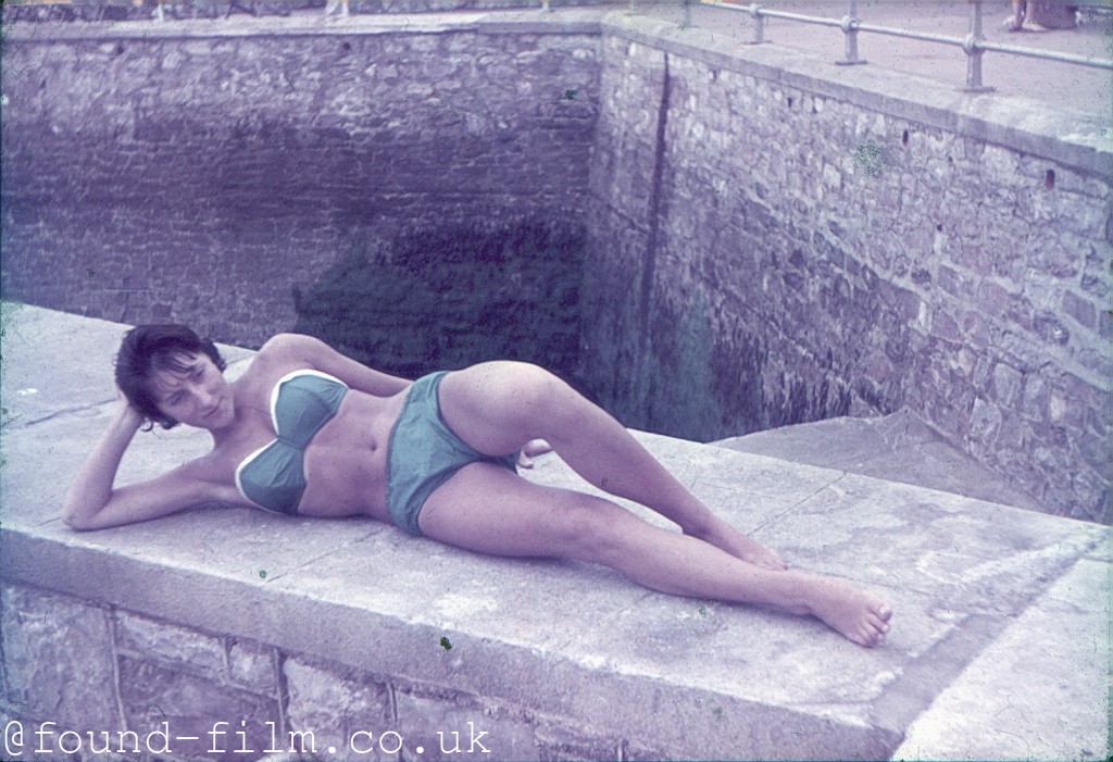 Girl in bikini posing on a concrete wall