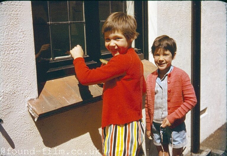 Two children standing by a window